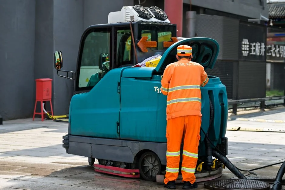 A person in full PPE disinfecting a table indoors for hygiene and safety.